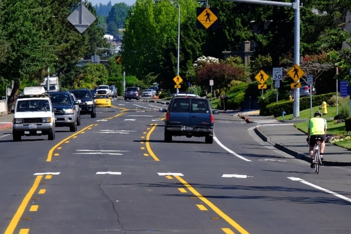 Image shows a biker and cars on the road together