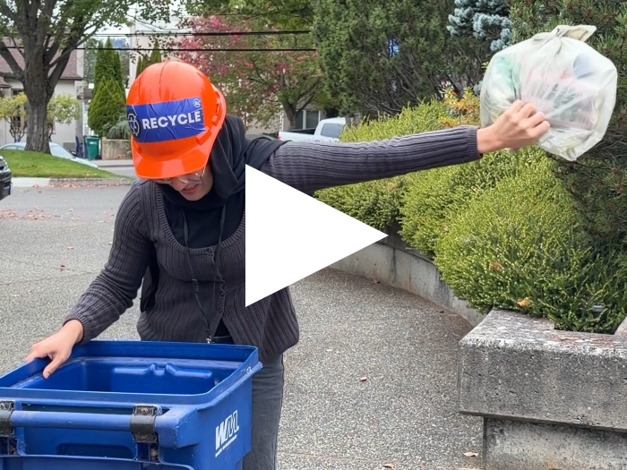 City employee blocks recyclables in a plastic bag from being thrown in the recycling bin