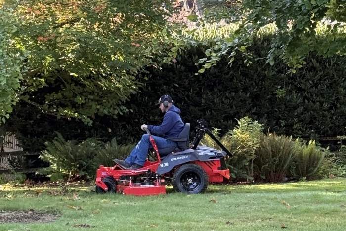 Image of City employee using an electric ride-on lawnmower as part of the "Mow, Edge, Blow Electric Equipment Pilot Program"