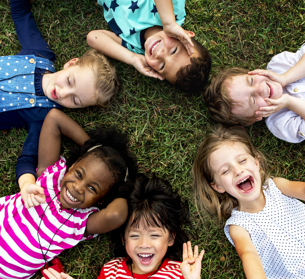 group of young multicultural kids lying on the grass and smiling