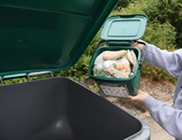 Person placing food scraps into the food and yard waste bin.