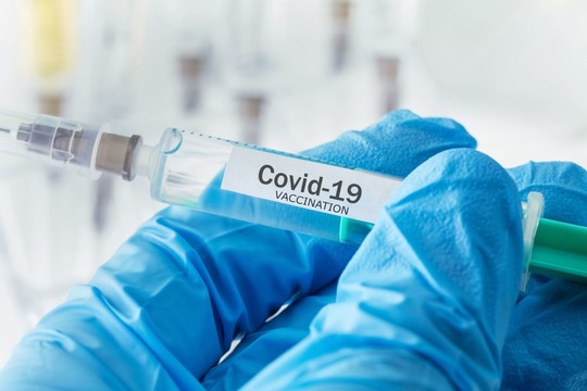 Vaccine needle held in blue glove