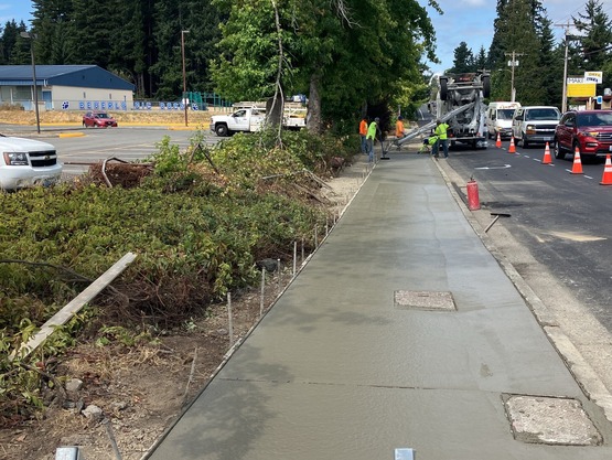 Crews pour concrete sidewalk along 52nd Ave W.