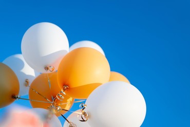 Gold and white balloons with blue sky background