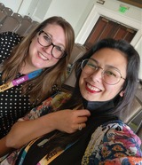 Photo of Kylie and Maria sitting in a room with empty chairs behind them at a conference