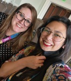 Photo of Kylie and Maria sitting in a room with empty chairs behind them at a conference