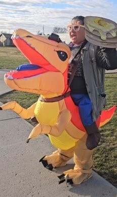 person in inflatable dinosaur costume holding giant pancakes