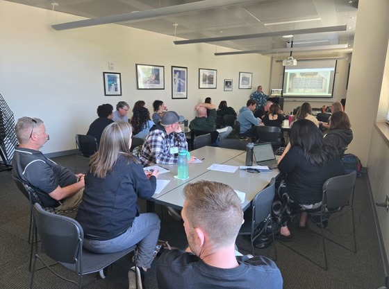 Groups of educators sitting around tables listening to a presentation.