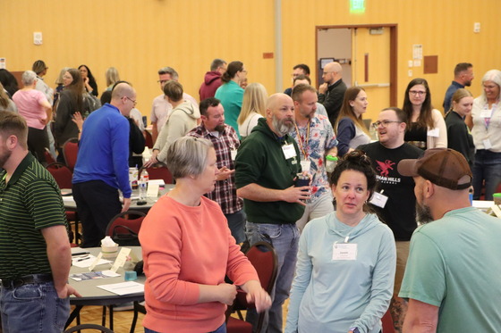 Educators in a large room speaking with each other in a group.