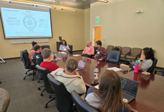 Educators sit at a conference table and discuss education strategies.