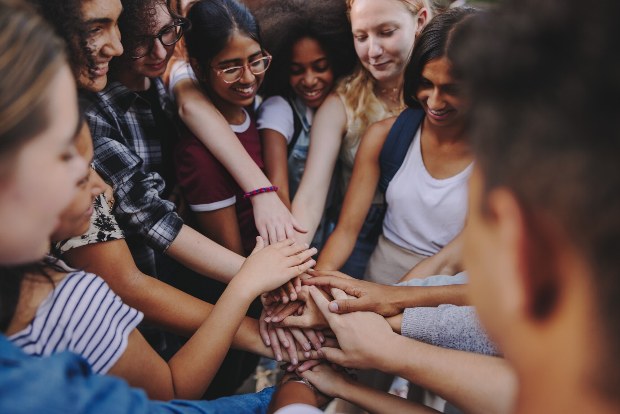 Community. Group of youth in a circle putting their hands together