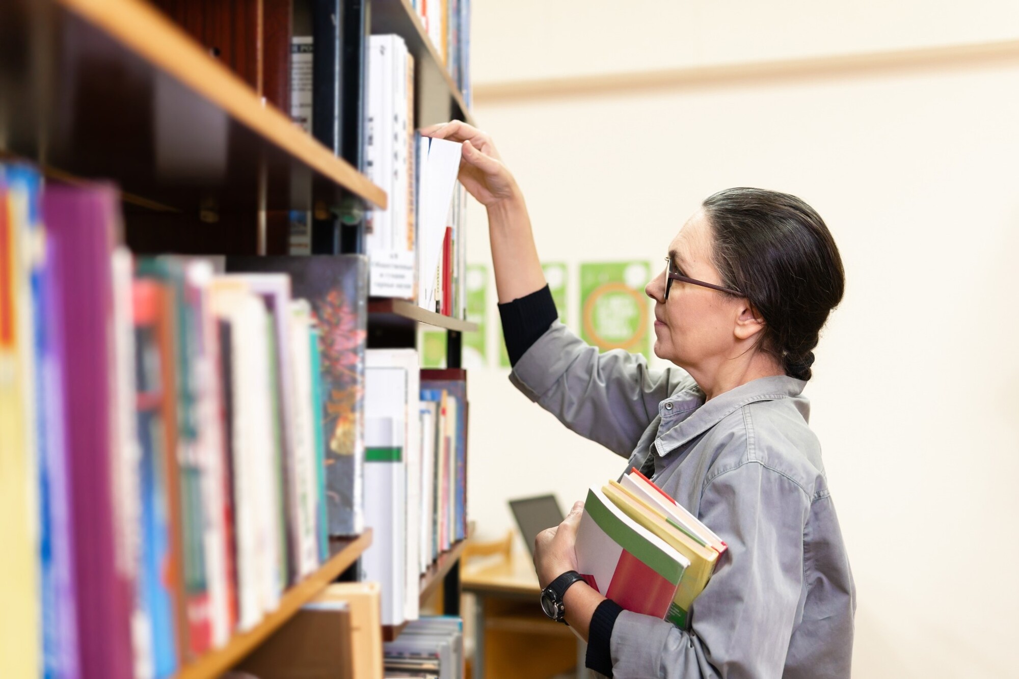 Resources Female educator pulling books from library