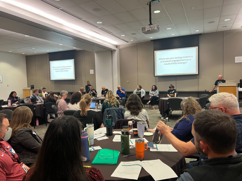 Attendees sit around tables and listen to a presentation during the Mastery-based Learning Collaborative 2026 Spring Gathering.