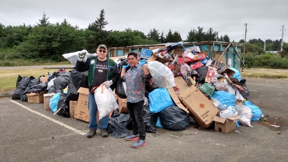 Fourth of July debris in a dumpster at the beach with volunteers cleaning it up.