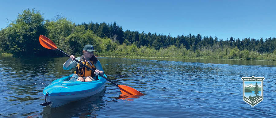 Person kayaking on lake with trees on shoreline