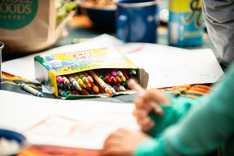 Kids hands with closeup of crayons and drawings around picnic table