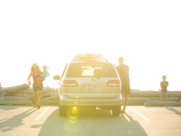 A family stands around a car in a parking lot.
