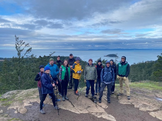 A group of hikers on a rock overlooking a body of water