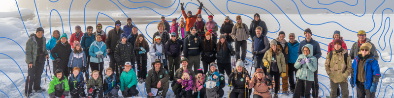 Big group of people standing in the snow after snowshoeing in front of Lake Wenatchee posing for a photo