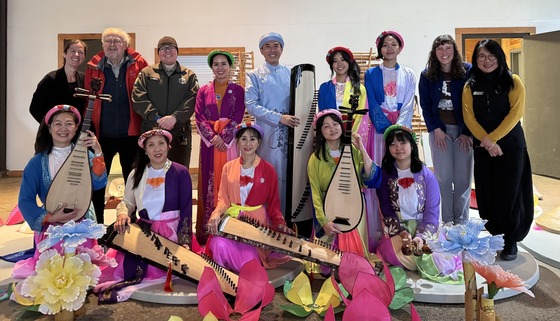 A group of people, including several in traditional Vietnamese dress with traditional musical instruments.