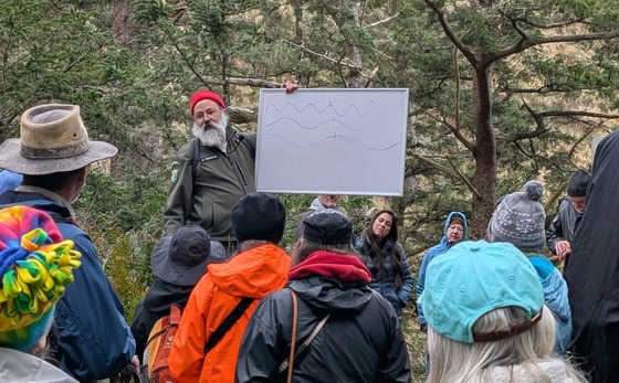 A park ranger leads a hike, showing props as he goes.
