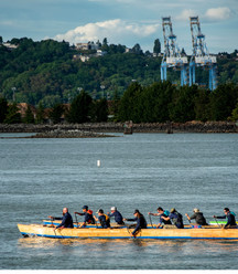 photo of people paddling a boat with cranes in the background