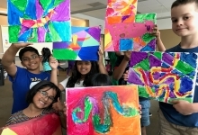 Kids holding up paintings they made