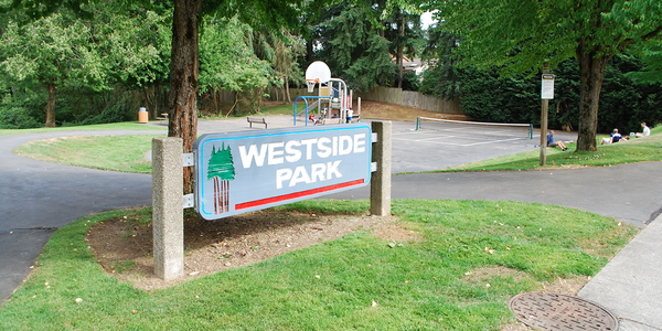 Westside Park entrance sign, playground in the background with kids climbing