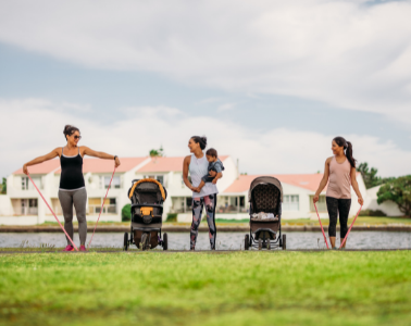 Three moms exercise in the park with their strollers and kids