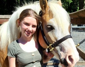 Student smiling next to a horse