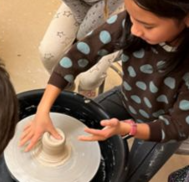 children using a small pottery wheel