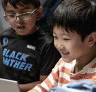 smiling children learning how to program video games on a laptop