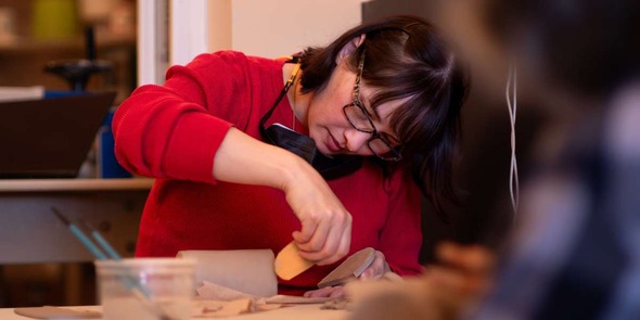 Adult hand-building a container out of clay