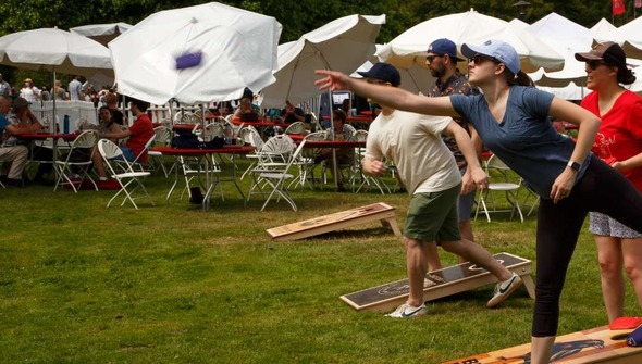 Adults playing cornhole outside during a festival