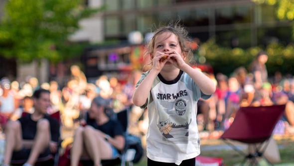 child dancing to music and playing a kazoo