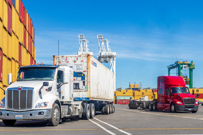 trucks driving between containers on a port terminal