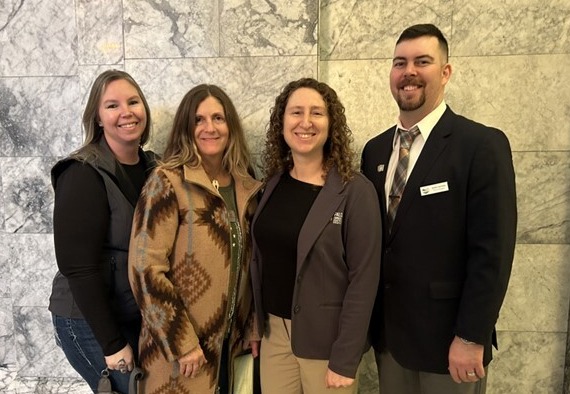 A picture of four people dressed up in front of a marble hallway.