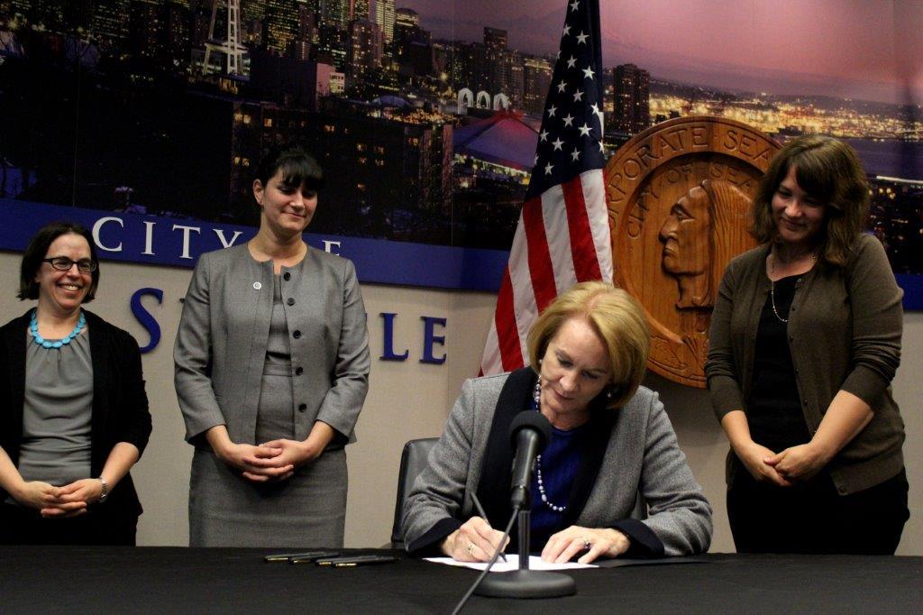 Mayor Durkan signs MFTE legislation with the Office of Housing Director Emily Alvarez and Office of Housing employees looking on
