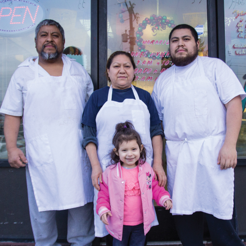 business owners and child, standing in the doorway of their small business