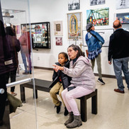 woman sitting with child on a bench looking at a museum exhibit