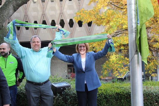 Mayor Durkan holds a Sounders FC scarf above her head at the flag raising at City Hall