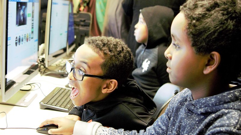 Two young men of color use a computer.