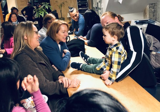 Mayor Durkan smiles as she greets a young boy seated on a table at her community celebration 