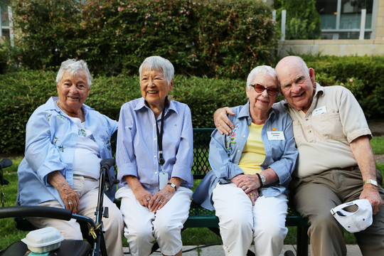 Photo of seniors smiling and sitting on a bench in nature