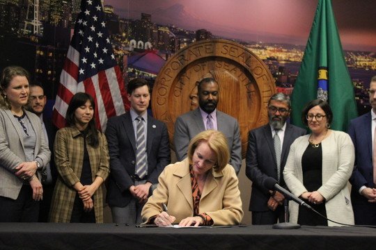 Mayor Durkan signs her climate EO surrounded by members of her cabinet.