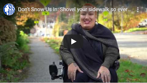 Screenshot of Rooted in Rights video with a smiling, red-haired woman seated in a powered wheelchair.