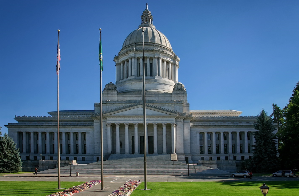 Photo of the Olympia Capitol Building, a large white marble building against a blue sky