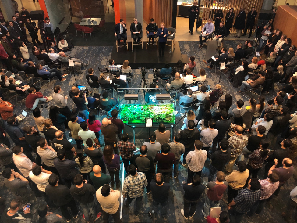 Ariel shot of Mayor Durkan, Chief Best, City Attorney Pete Holmes, and Councilmember Lewis speak to a large crowd of assembles Amazon employees