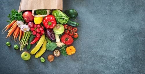 Image of a bag of fresh vegetables spilling out over a charcoal colored counter 