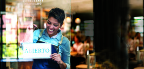 Store owner turning sign that says 'abierto'